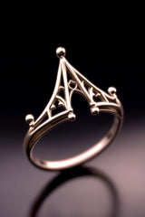 Gold ring with intricate design on a dark background