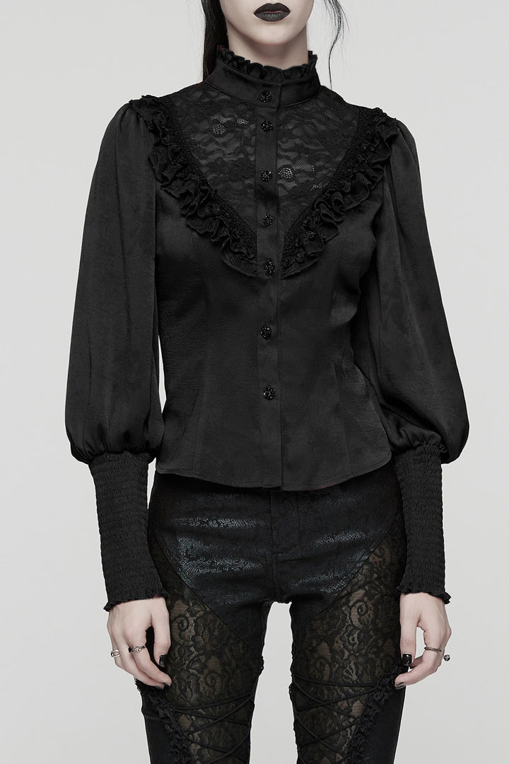 Person wearing a black lace blouse and black pants on a plain background