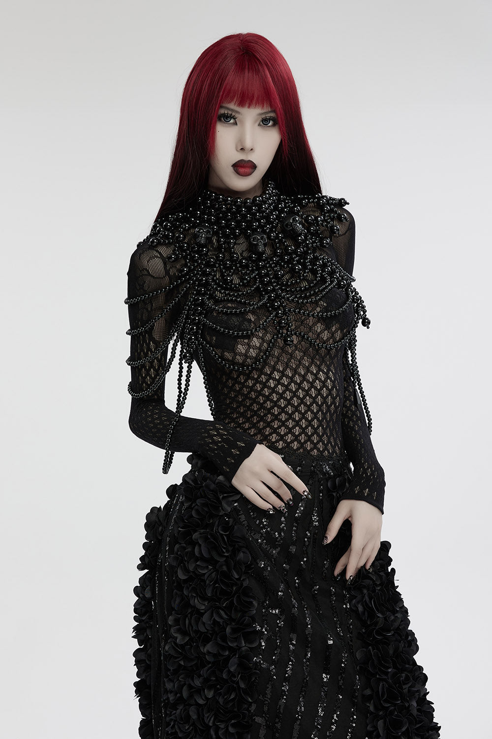 Person wearing a black, intricate dress with red hair on a white background