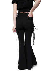 Rear view of a model wearing black flared pants with side tie details and a black ruffled top against a white background.