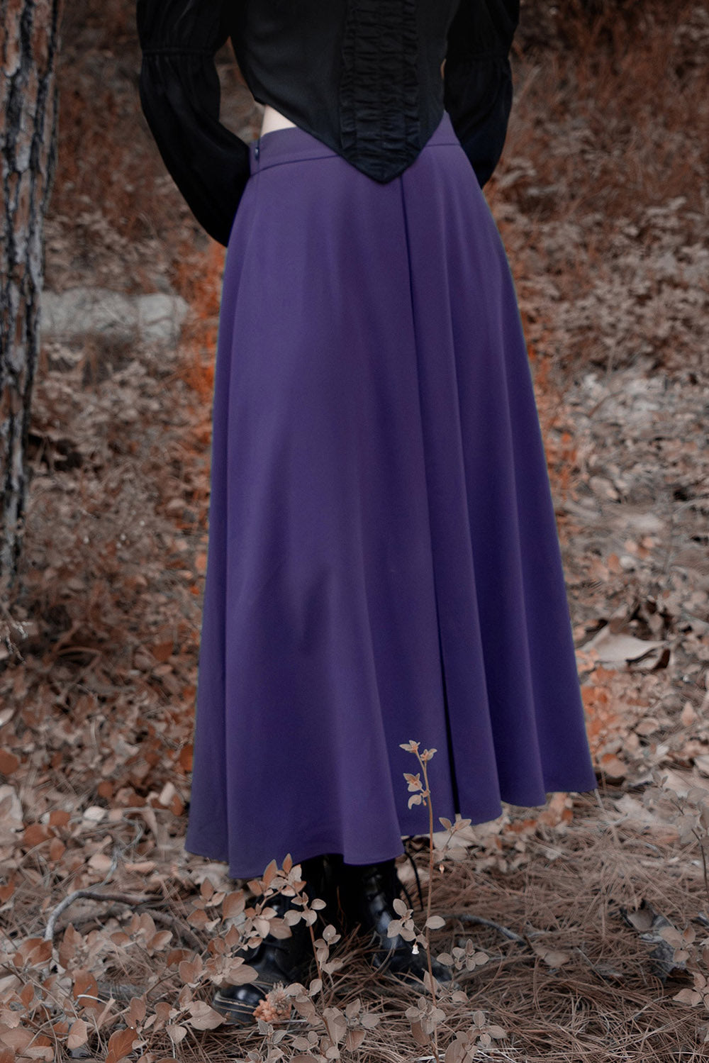 Person wearing a long purple skirt with a textured background