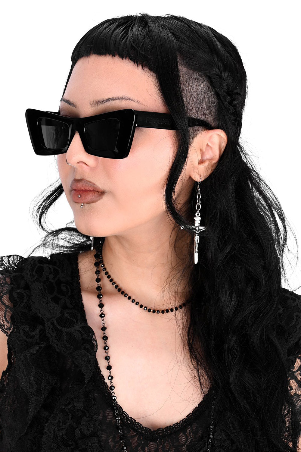 Person wearing black rockabilly cateye  sunglasses and a black lace top with a white background