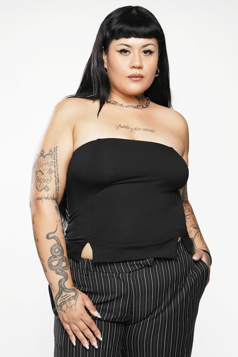 Person wearing a black strapless top and pinstripe pants on a white background