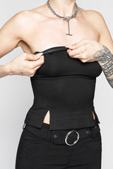 Person wearing a black strapless top and pants with a belt, on a plain background