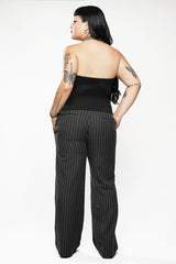 Person wearing a black strapless top and pinstripe pants on a white background