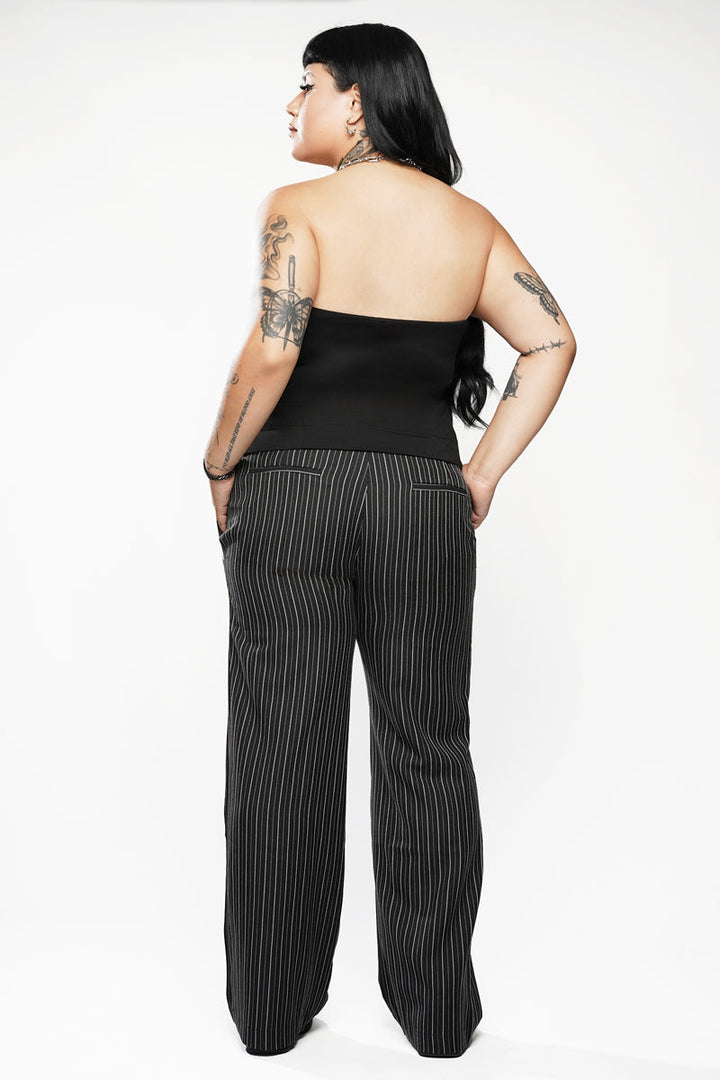 Person wearing a black strapless top and pinstripe pants on a white background