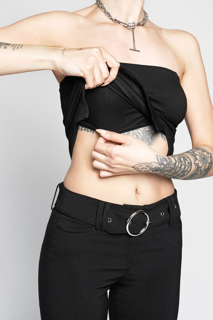 Person wearing a black strapless top and black pants with a plain background