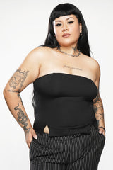 Woman wearing a black strapless top and pinstripe pants on a white background