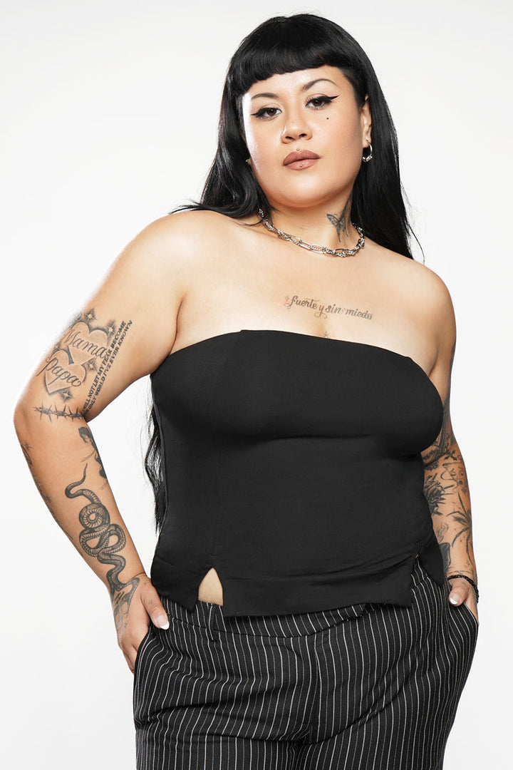Woman wearing a black strapless top and pinstripe pants on a white background
