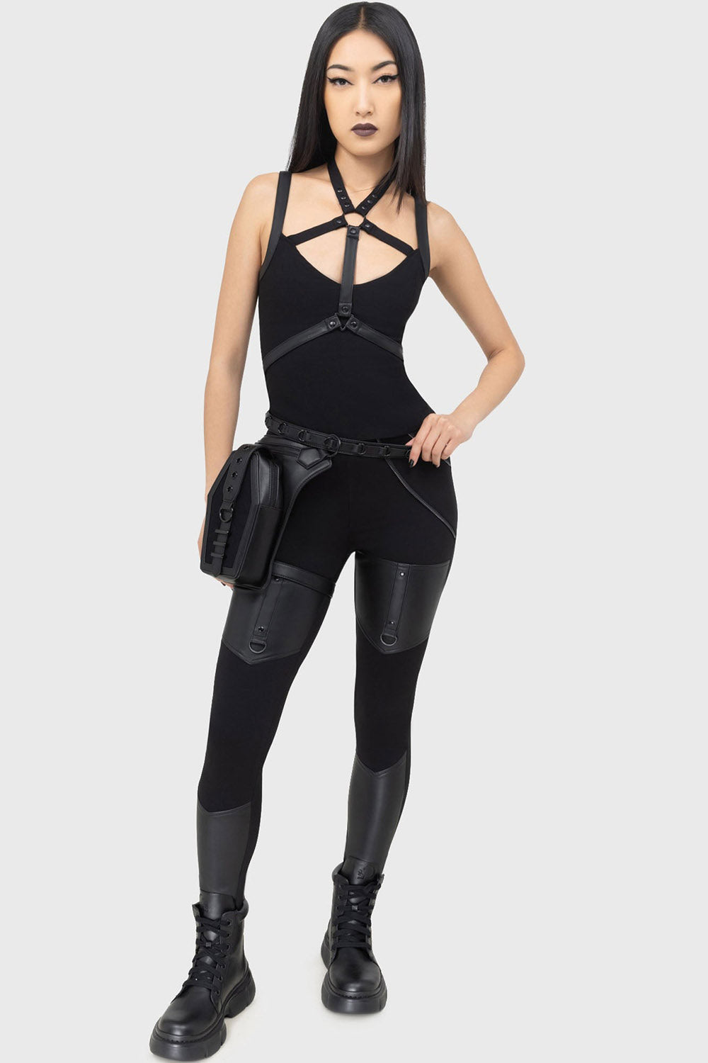 Person wearing a black outfit with gothic holster hip bag on a white background