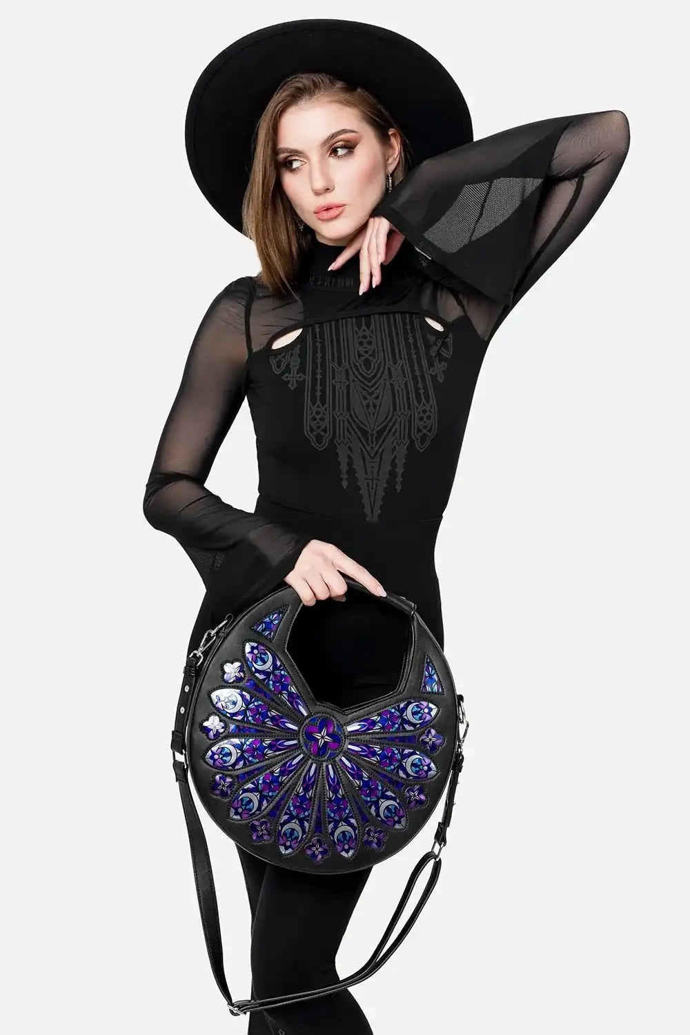 Woman holding a black handbag with intricate design on a white background