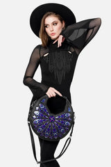 Woman holding a black handbag with intricate design on a white background