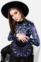 Woman wearing a black hat and a colorful outfit holding a matching handbag against a white background
