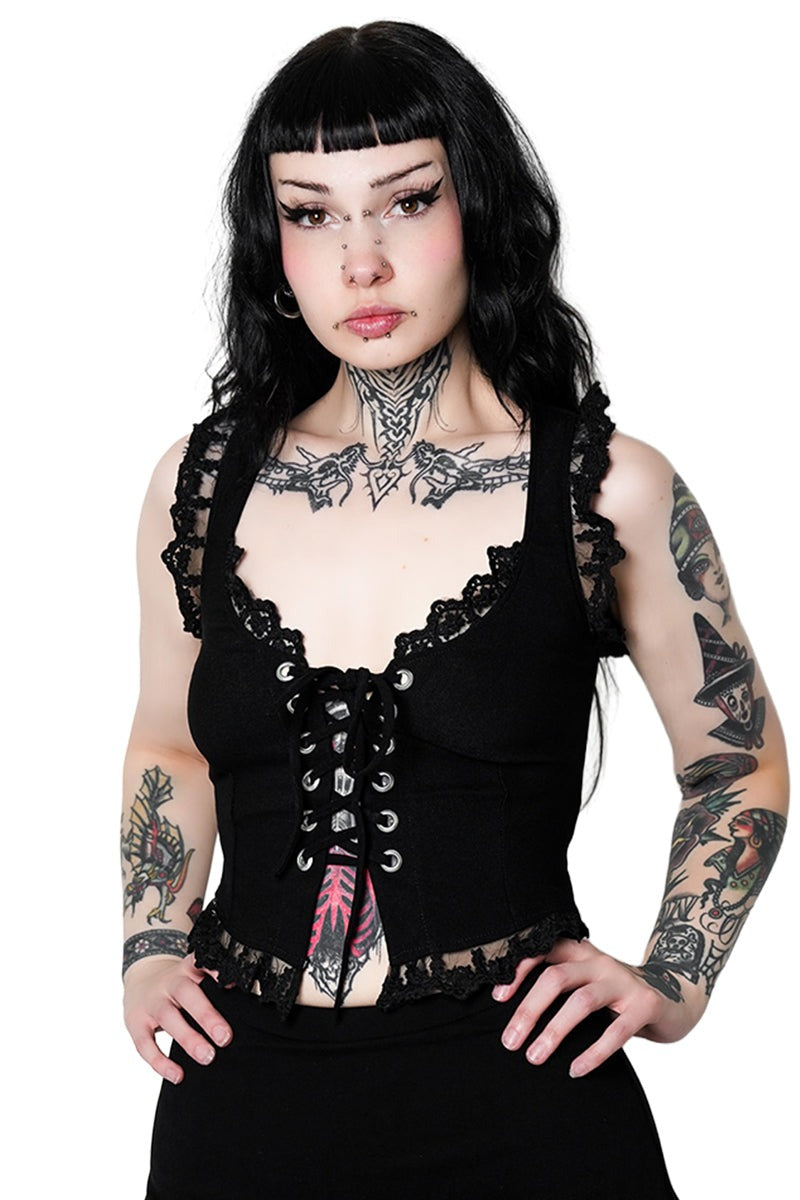 Woman wearing a black lace corset with tattoos on her arms and neck against a white background