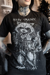Person wearing a black t-shirt with a graphic design and text 'Stay Trashy' featuring a raccoon