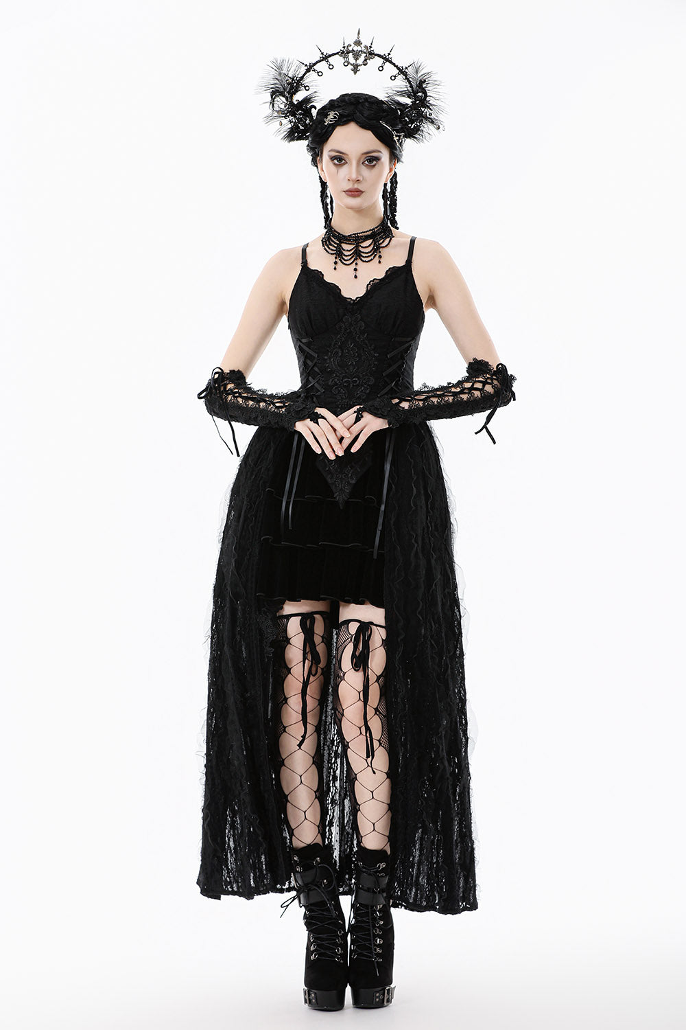 Woman in a black gothic dress with lace sleeves and accessories on a white background