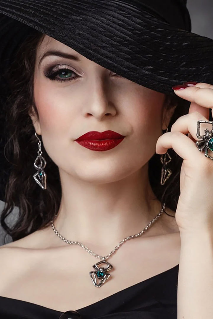 Woman wearing a black hat, red lipstick, and spider jewelry with a dark background