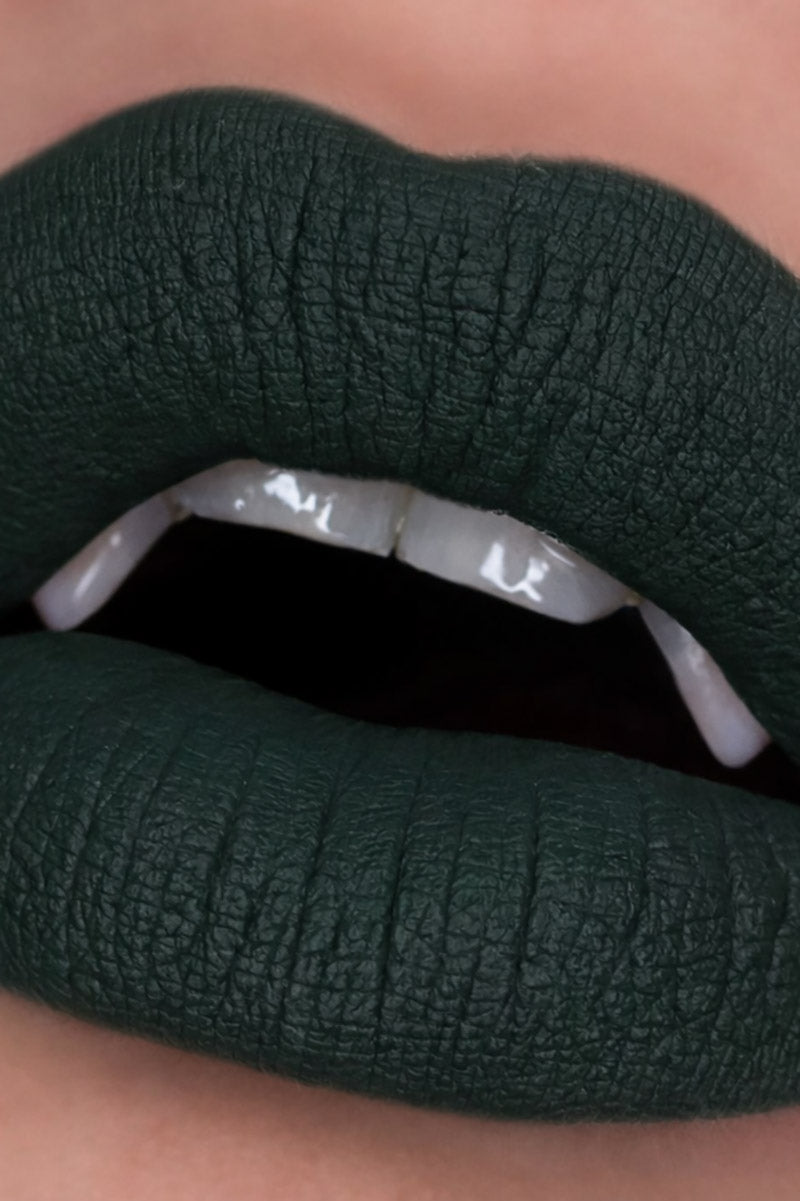 Close-up of dark green lipstick on a neutral background