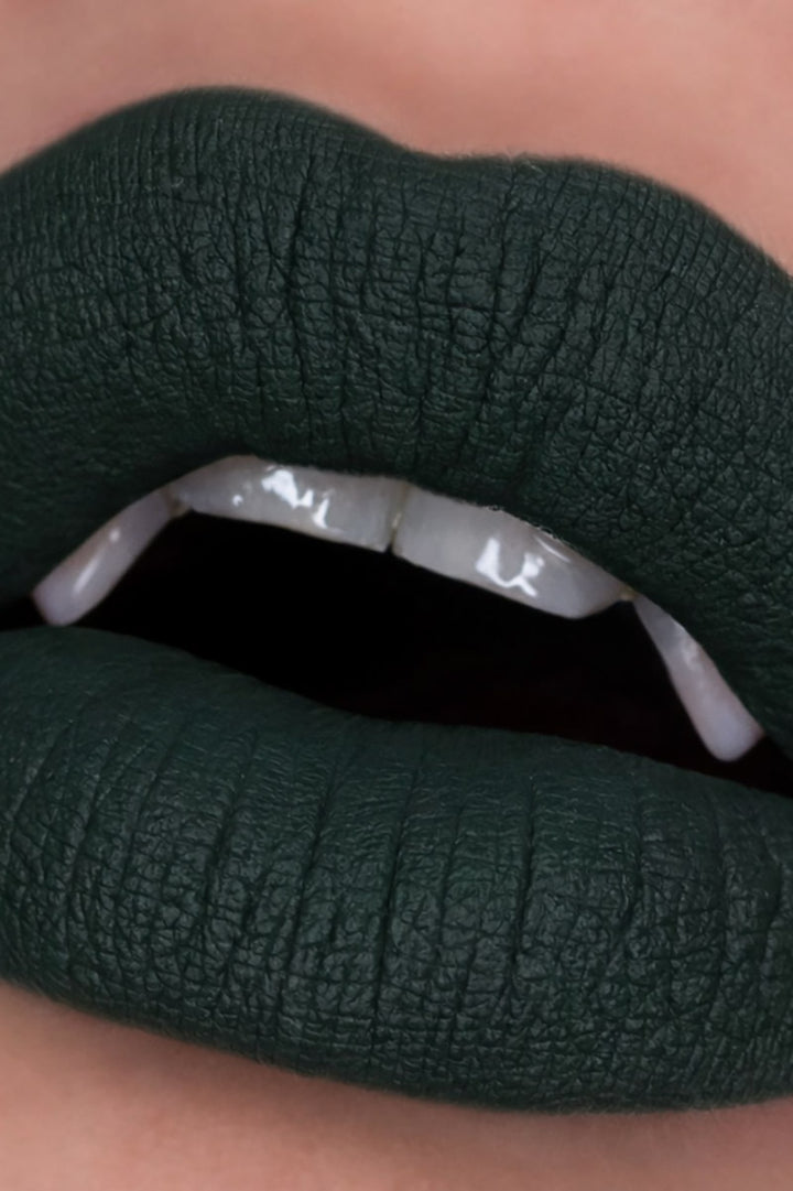 Close-up of dark green lipstick on a neutral background