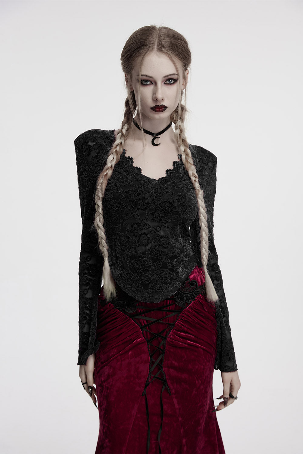 Woman in gothic attire with braided hair and dark clothing on a white background