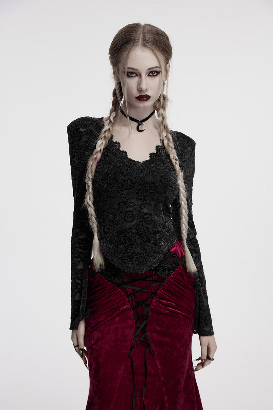 Woman in gothic attire with braided hair and dark clothing on a white background