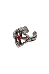 A silver-toned metal ring with a textured, sculptural design featuring a small, square-cut red gemstone in the center, set against a plain white background.