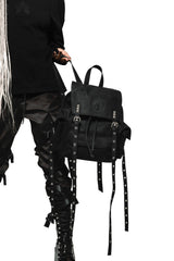 Black backpack with straps held by a person wearing black clothing on a white background