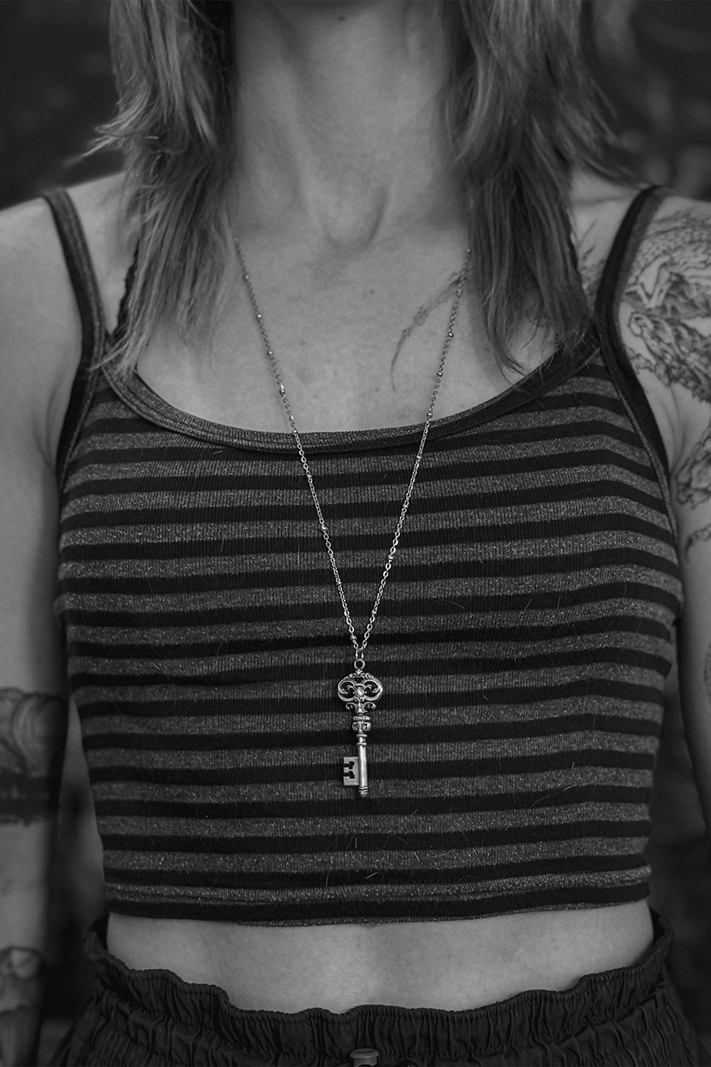 tattooed woman wearing a gothic key necklace