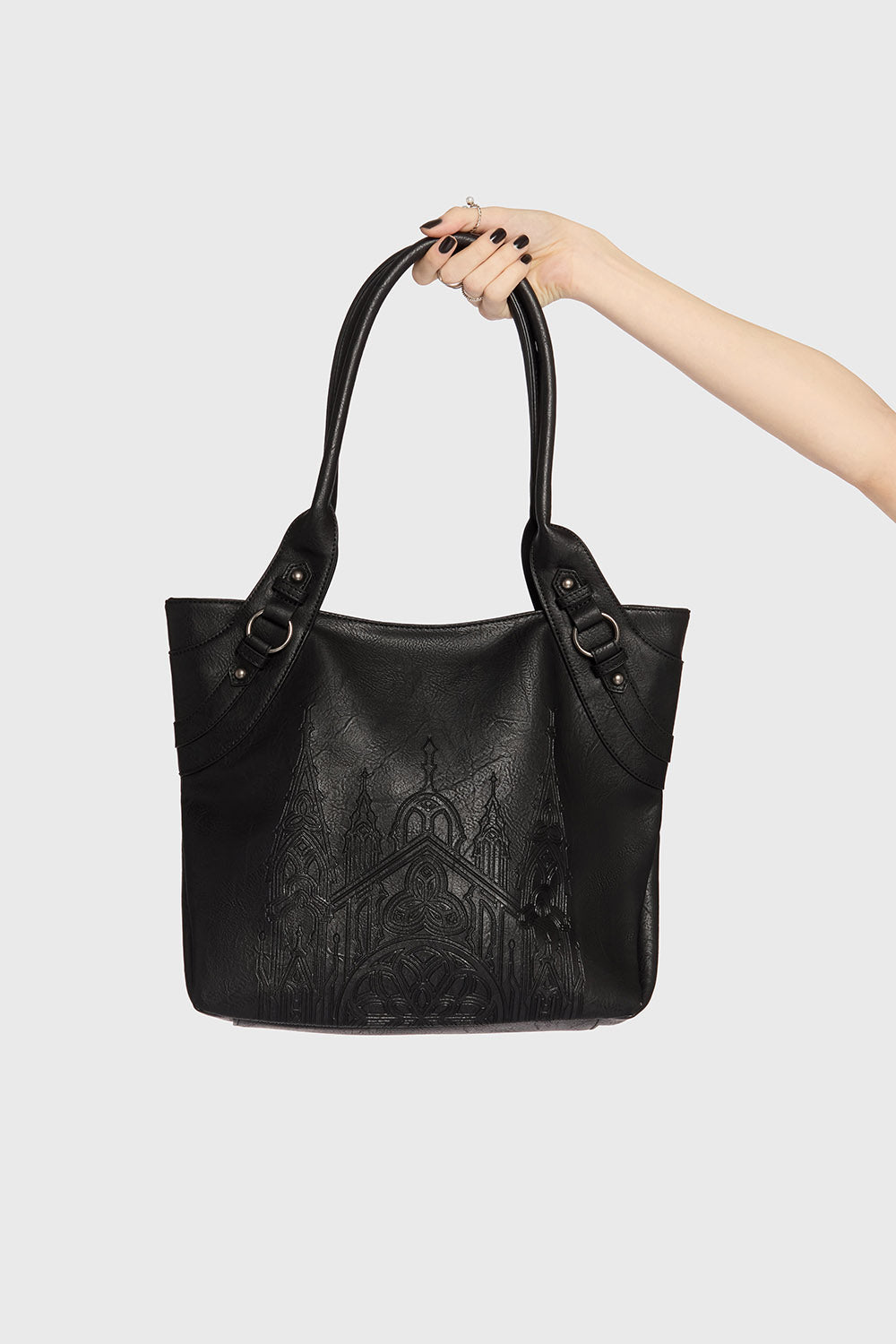 Black handbag with intricate design held by a hand against a light gray background