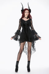 Woman wearing a black lace dress with long sleeves and a high-low hemline on a white background.