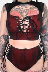 Red and black corset bikini with floral patterns on a tattooed person