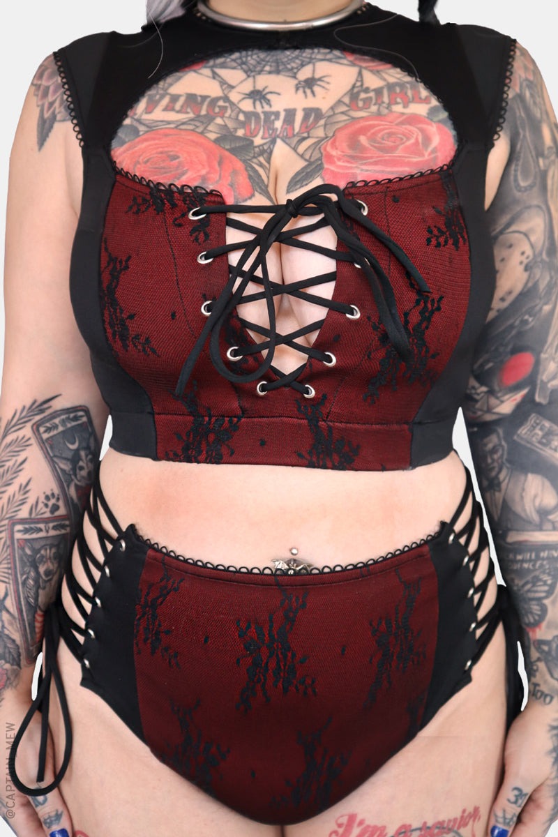 Red and black corset bikini with floral patterns on a tattooed person