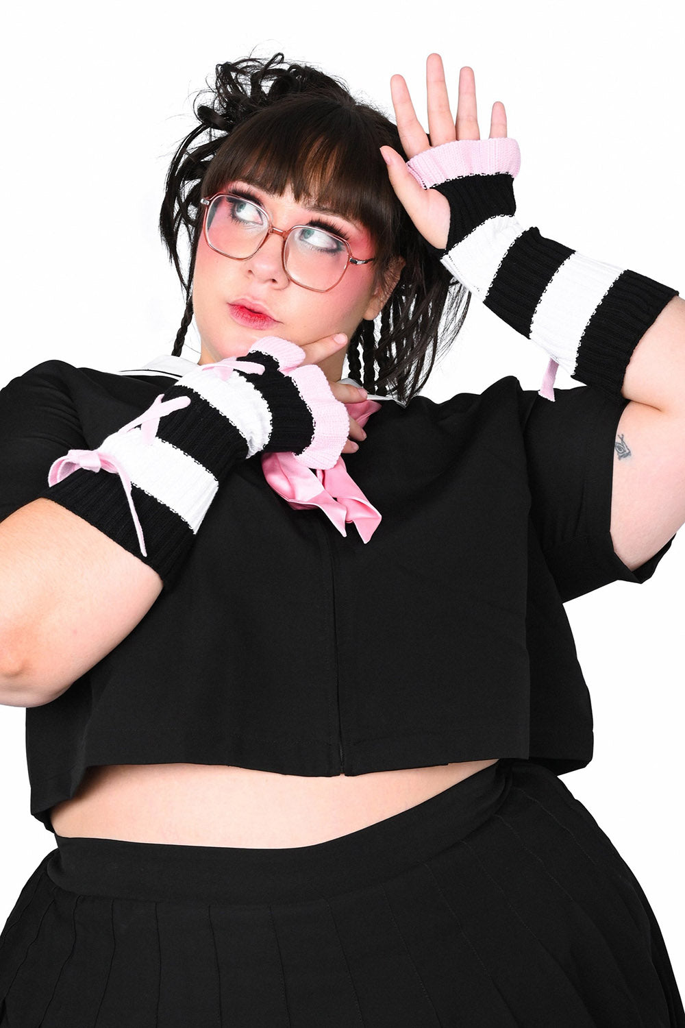 Person wearing a black outfit with striped fingerless ruffled gloves on a white background