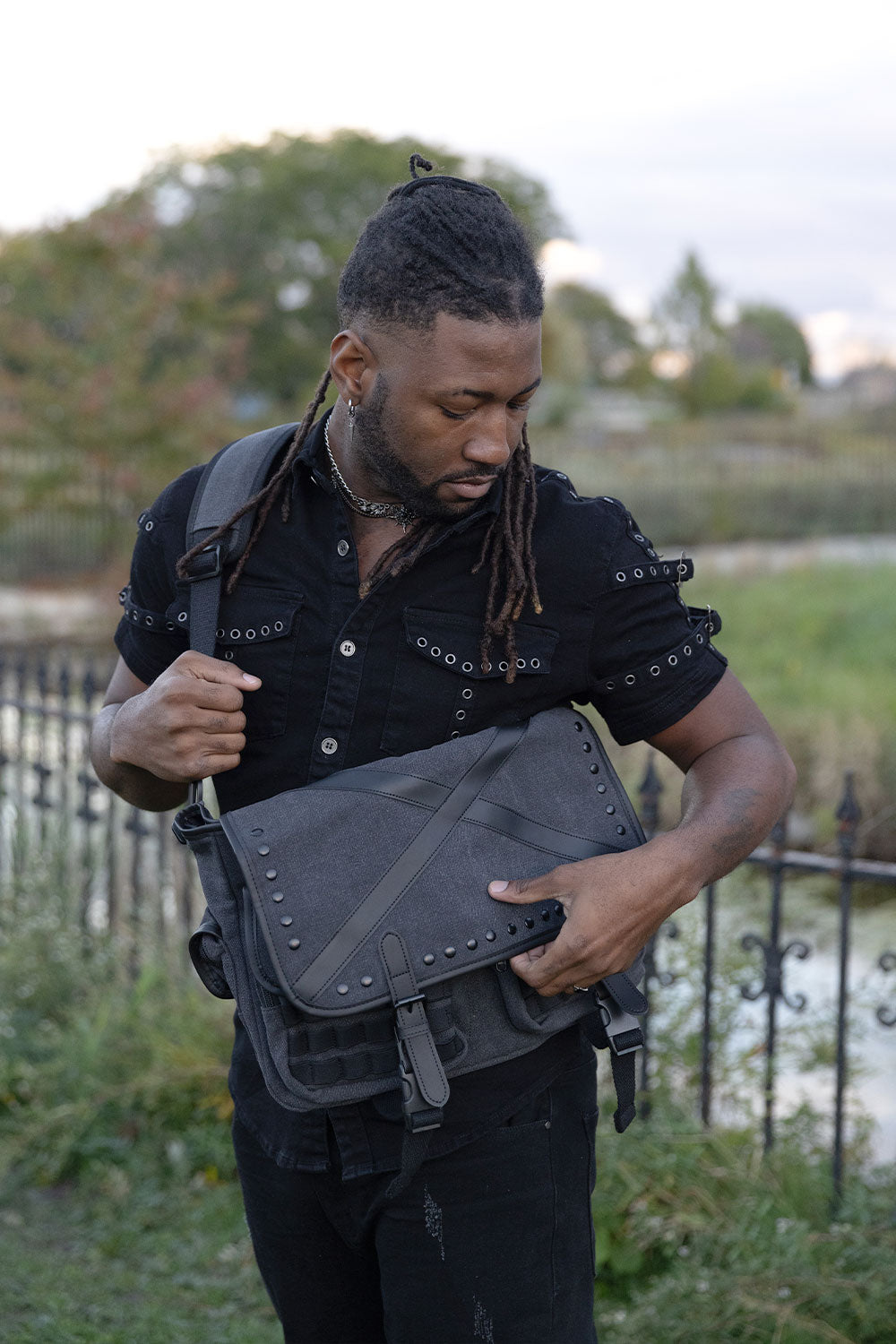 Alternative gothic shoulder bag with black studded hardware buckle straps and multiple storage pockets for emo punk grunge and dark aesthetic fashion
