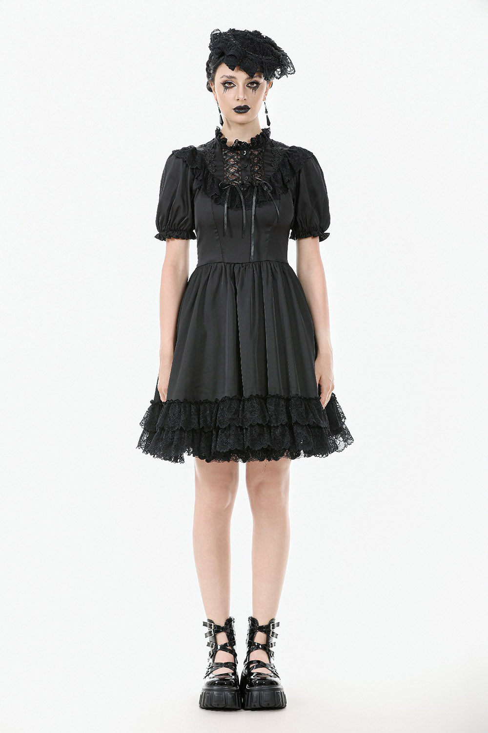 Woman wearing a black gothic-style dress with lace details on a white background