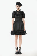 Woman wearing a black gothic-style dress with lace details on a white background
