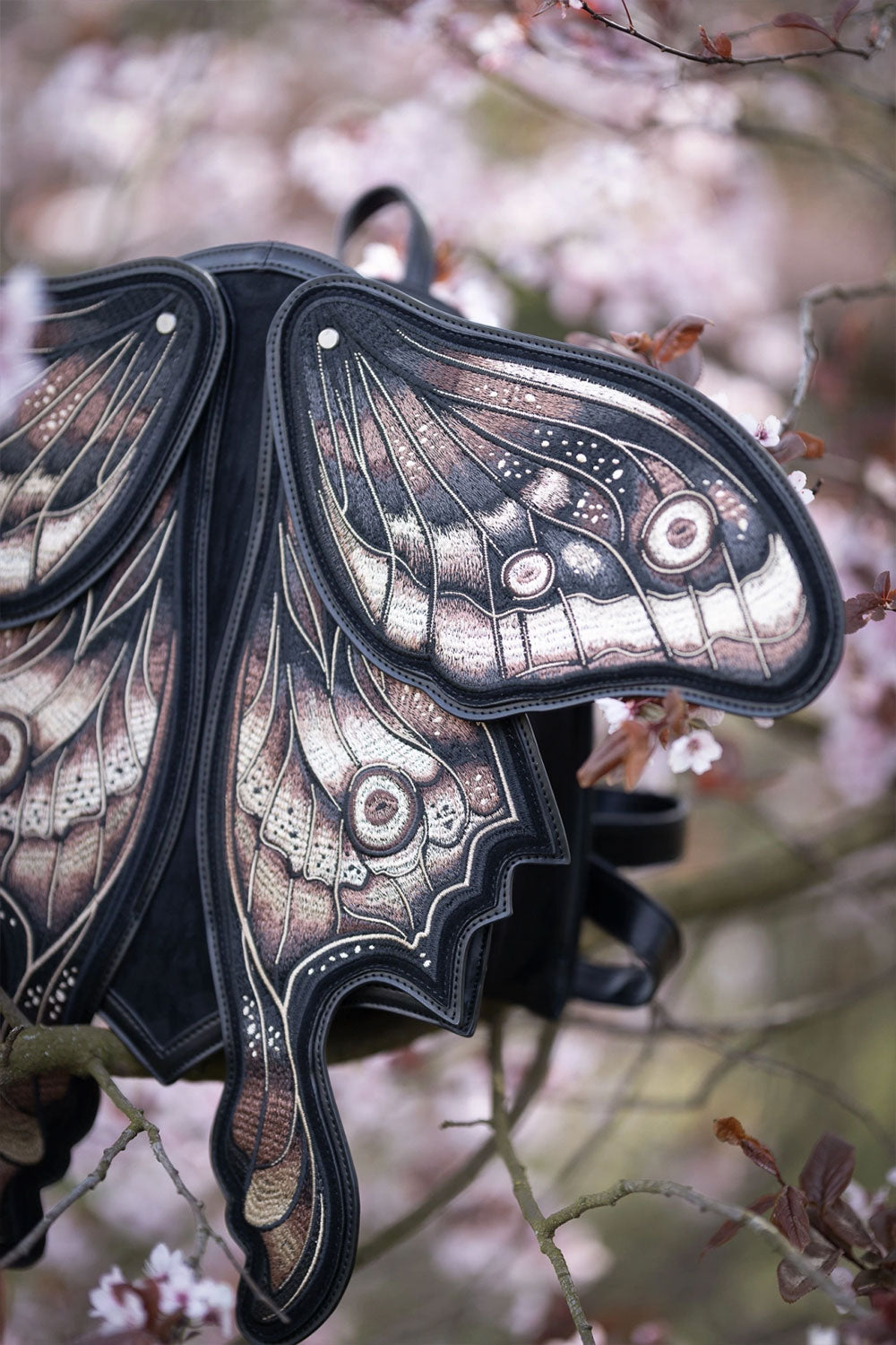 Moth backpack with shield-shaped base made of black faux suede