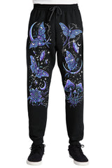 Black sweatpants with a vibrant blue and purple celestial print featuring moths, mushrooms, flowers, and stars, shown on a model from the waist down against a white background.