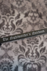 Notebook with 'The Nightwatcher's Notebook' title on a decorative background