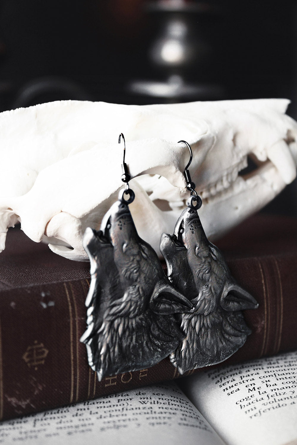 Wolf-shaped earrings on a skull with an open book