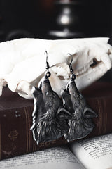 Wolf-shaped earrings on a skull with an open book