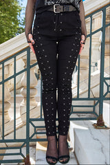 Black skinny pants with eyelet lace-up detailing, shown on a model standing on stone steps.