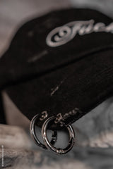 large silver rings pierced through a textured goth hat