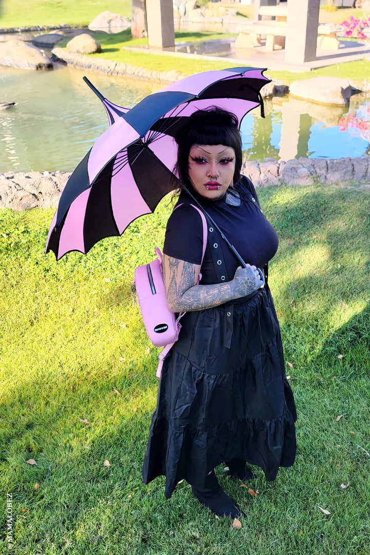 goth girl holding pink and black stripe umbrella