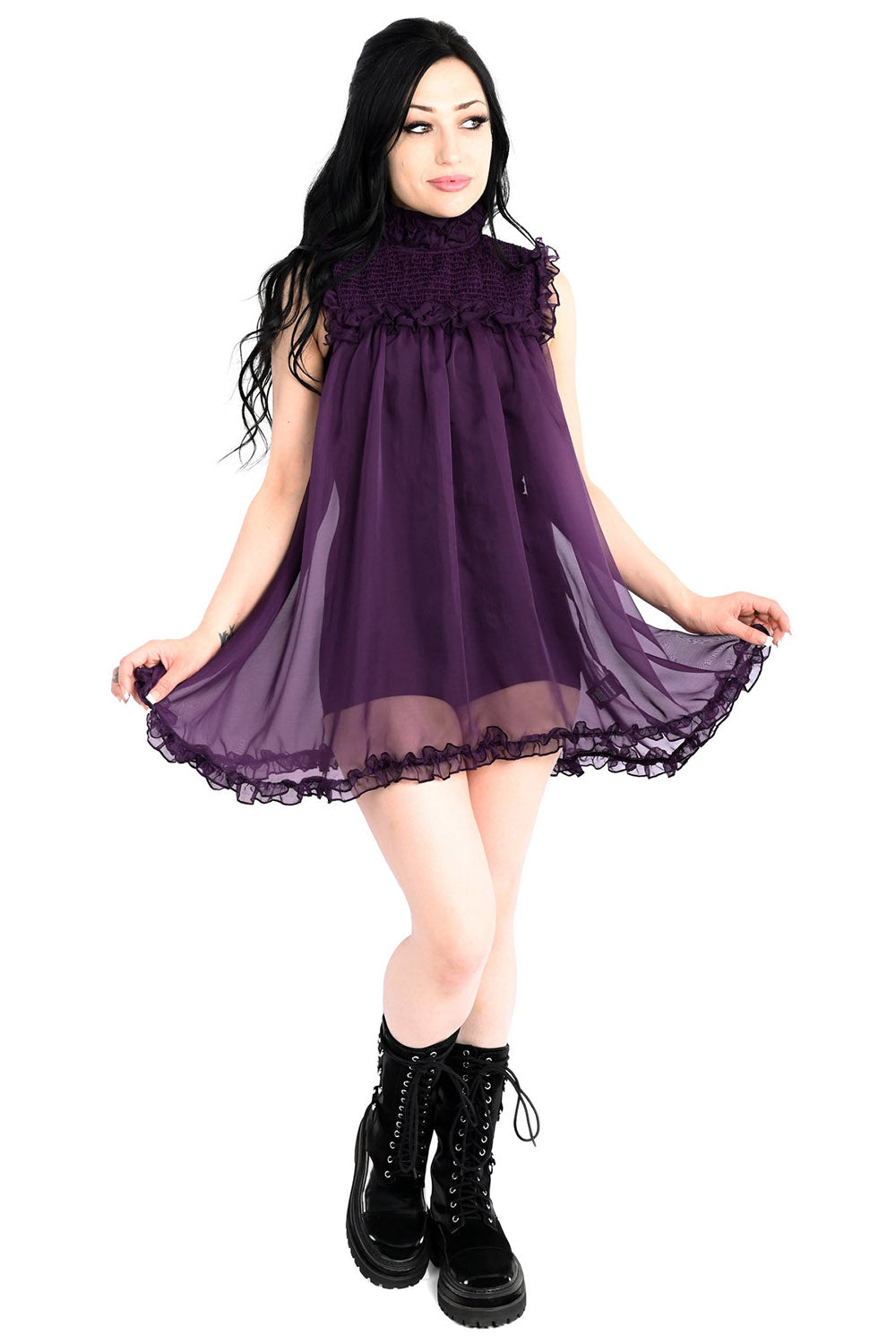 Woman wearing a purple dress with black boots on a white background