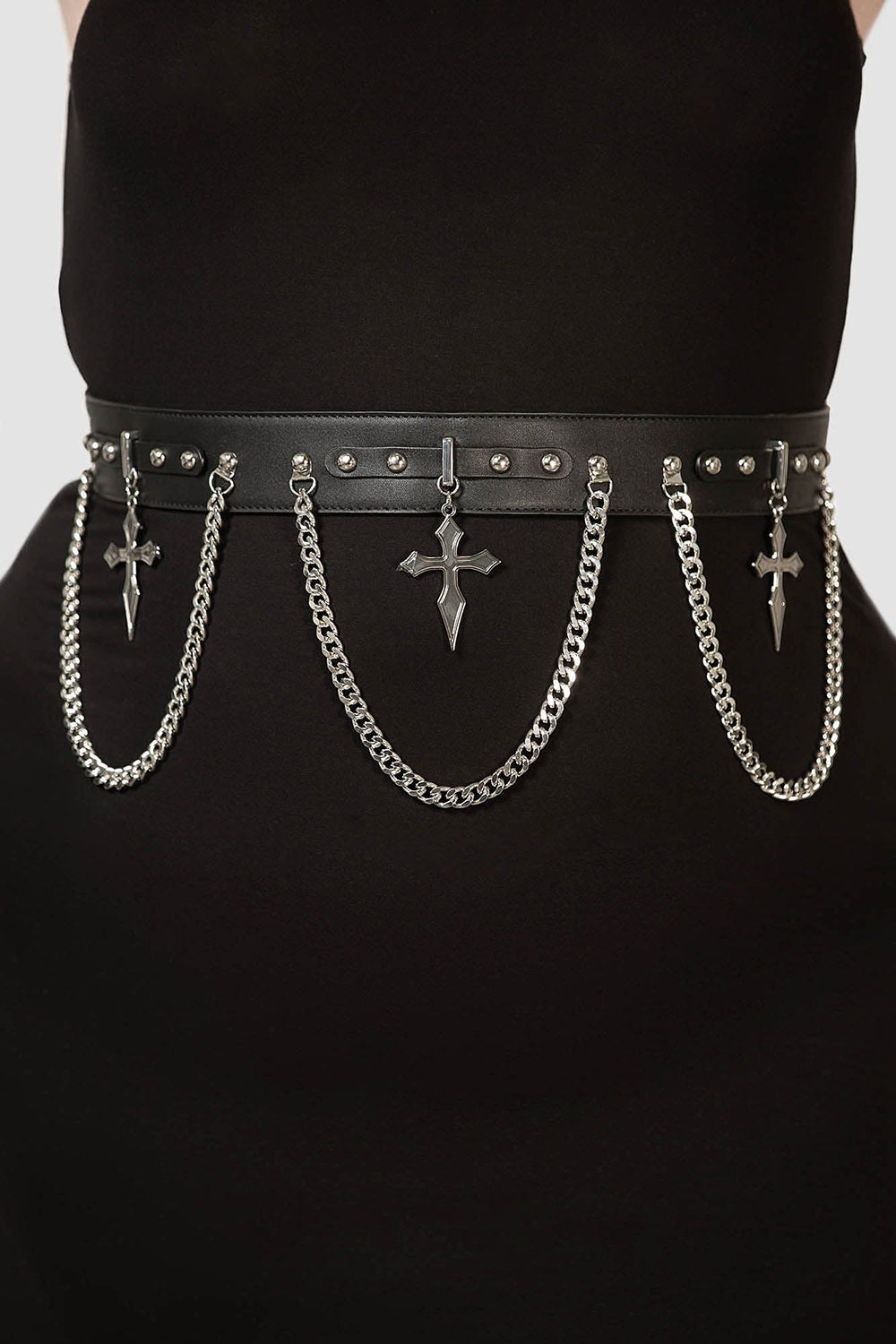 Black belt with chains and crosses worn by a person on a plain background