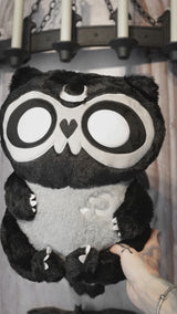 video of a grey and black embroidered moon raccoon plush toy