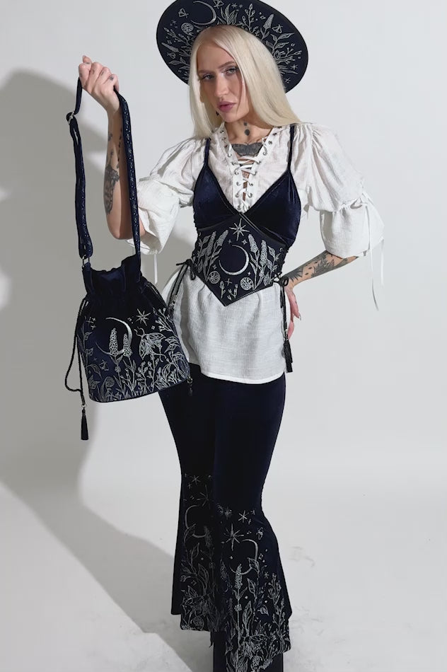 video of a gothic woman wearing a dark blue velvet embroidered moon and moth shoulder bag