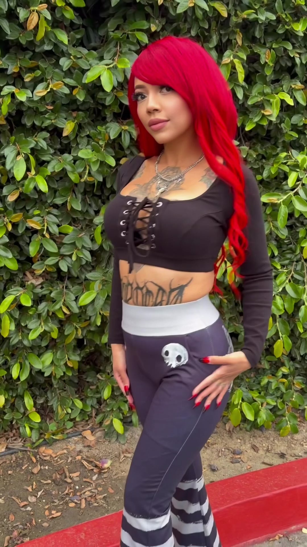 emo woman with red hair wearing creepy cute striped flared pants