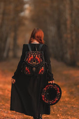 video of a dark witchy woman wearing a embroidered dark cottagecore backpack